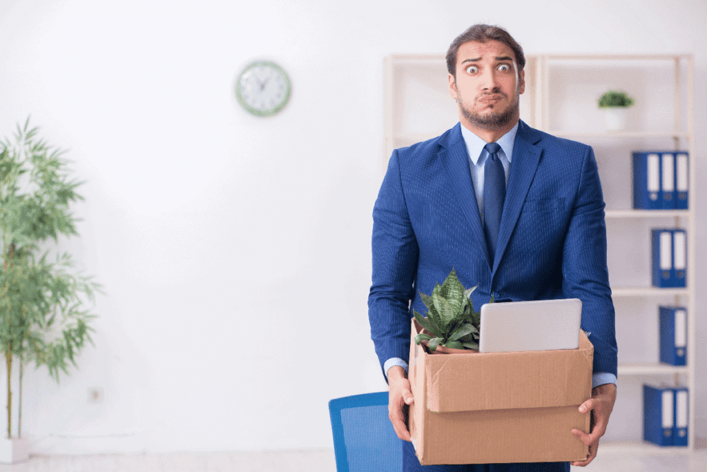 Guy in blue suit with a box in his hands after getting fired.